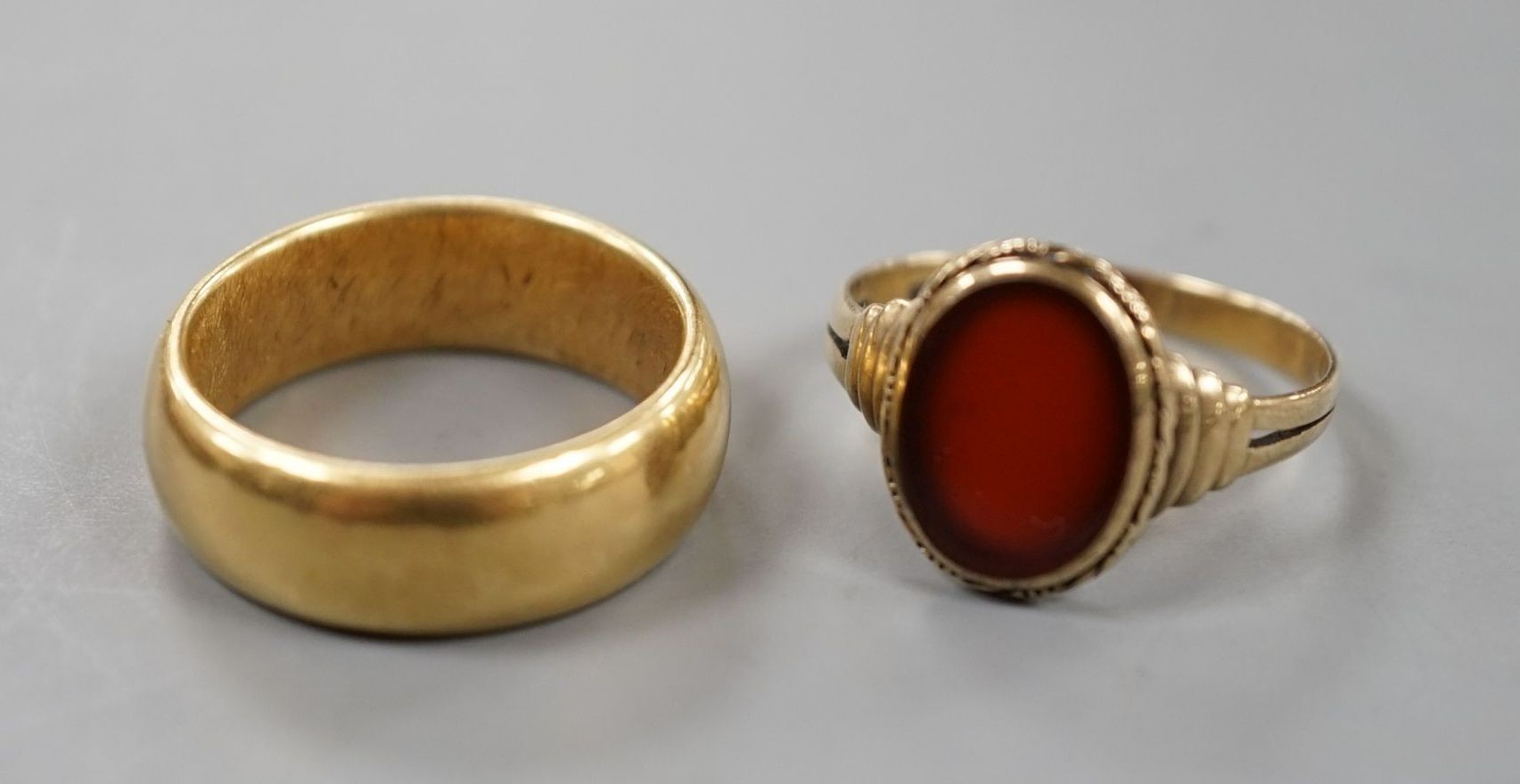 A George V 18ct gold wedding band, size Q, 14 grams and a 333 standard yellow metal and carnelian set signet ring, size R, gross weight 2.8 grams.